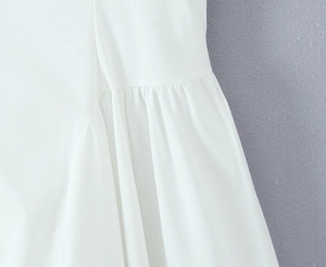 Détail de robe blanche montrant des coutures plissées élégantes et une texture de tissu fin