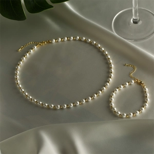 Elegant pearl and gold bead jewelry set displayed on silk with soft natural lighting