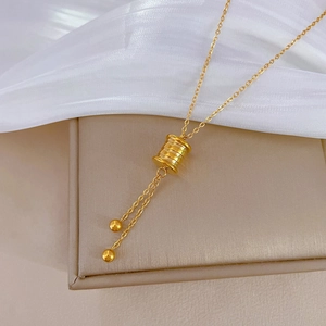 Macro detail of golden spring cylinder necklace pendant with tassel chain on jewelry box