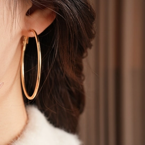 Close-up of vintage style large gold hoop earrings with polished metallic finish