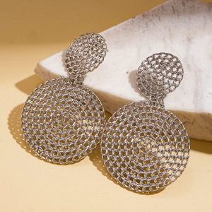 Détail macro de boucles d'oreilles géométriques en maille argentée sur pierre