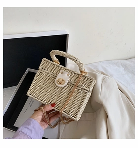 Detaillierte Nahaufnahme der cremefarbenen Strohtasche mit Goldkette und Drehverschluss