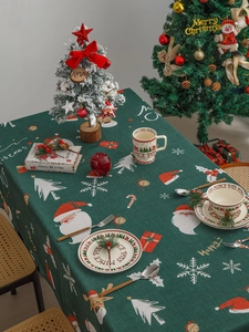 Detail of Nordic green Christmas tablecloth with Santa and reindeer prints on cotton fabric