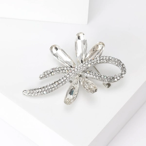 Macro view of crystal bow brooch with clear rhinestones on polished silver-tone alloy base