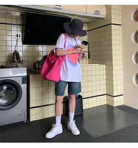 Lifestyle view of a large rose red canvas shoulder bag styled with casual summer outfit