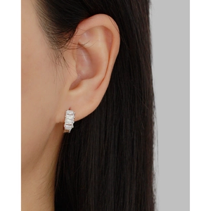 Close-up of a silver S925 hoop earring with rectangular zircons on a model ear
