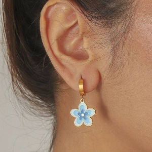 Boucles d'oreilles fleur en émail bleu plaqué or portées par un mannequin