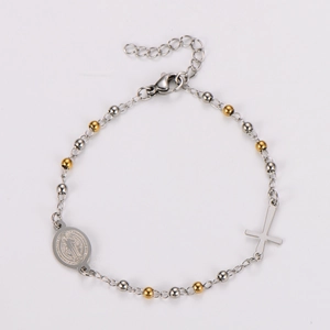 Macro detail of bicolored beaded bracelet with cross pendant and religious medallion