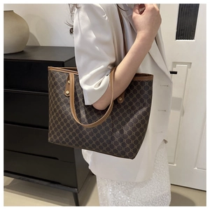 Side view of large vintage tote bag with dark brown monogram pattern and leather handles