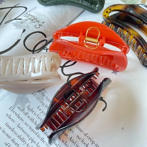 Close-up of assorted large butterfly hair claws in red, green, and beige tones