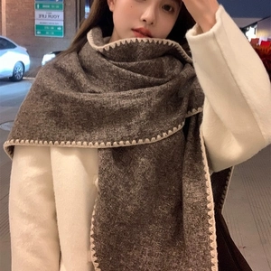 Brown knit triangle shawl with beige scalloped edges worn by model in street night view