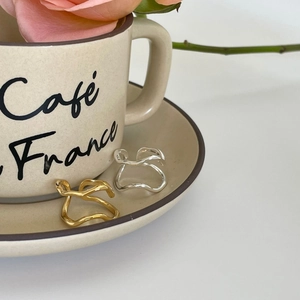 Irregular liquid wave open rings in gold and silver finish on a ceramic coffee tray