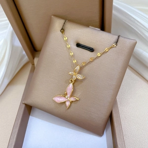 Gold butterfly necklace with pink enamel and crystals displayed on a jewelry box cushion