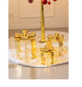 Detail of three golden Christmas gift boxes with LED lights on a white plush carpet