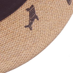 Macro view of woven straw sun hat featuring dark fish pattern and blue ribbon trim