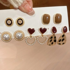 Detail view of resin pearl earrings set with heart and leopard patterns on display card