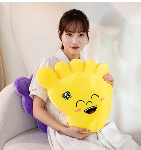 Close-up of soft yellow big foot plush pillow with embroidered smile and spider pattern