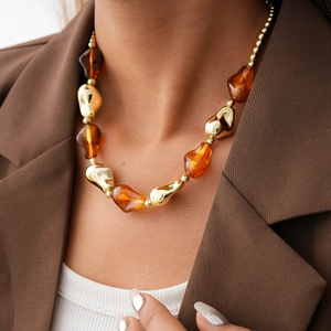 Detail of a vintage acrylic geometric necklace with amber beads on a model's neck