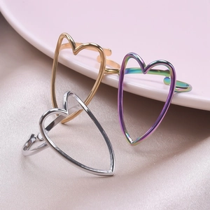 Three open heart rings in gold, silver and iridescent finishes on silk background