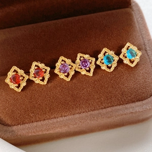Macro shot of three pairs of vintage gold earrings with red, purple, and blue zircon crystals