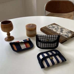 Detailed view of canvas coin purses in houndstooth and striped woven fabric on a white table