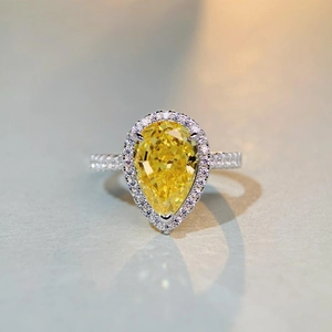 Macro view of pear cut yellow gemstone ring with halo diamonds on silver band