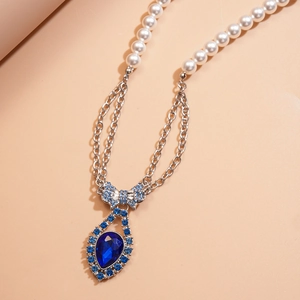Detailed view of the sparkling blue rhinestone bow and teardrop crystal pendant on the necklace