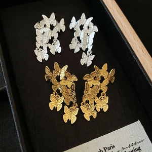 Eleganti orecchini pendenti a farfalla in finiture oro e argento su una scatola nera