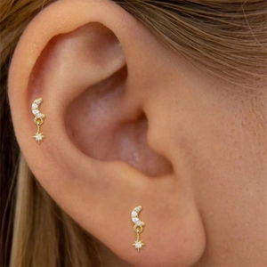 Detailed view of S925 silver golden crescent moon and star earrings worn on ear cartilage