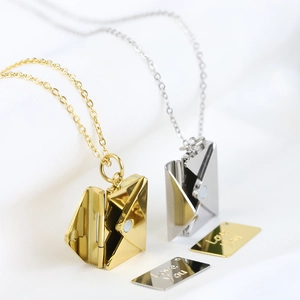 Detailed view of gold and silver envelope necklaces with Love You engraved inserts