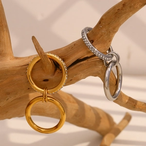 Detail of 18K gold and silver double-hoop earrings with rhinestones on wooden branch