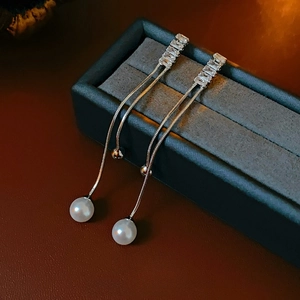 Silver chain tassel earrings with square zirconia and pearls on dark jewelry box