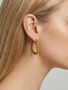 Close-up of gold-plated U-shaped geometric earrings with textured wavy surface on model