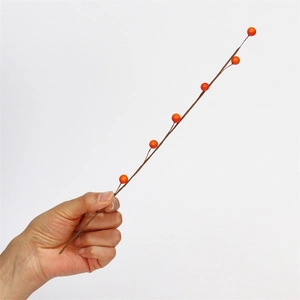 Detail of hand-held artificial orange berry branch for home decor and DIY arrangements