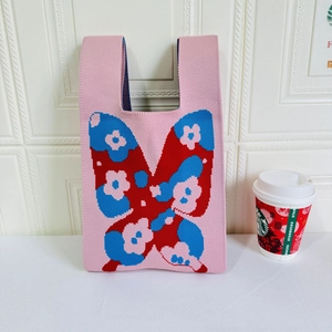 Close-up of knit tote bag with colorful butterfly patterns and floral textures