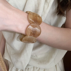 Detail of amber acrylic resin chunky bracelet with semi-transparent swirl textures