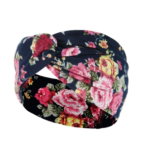 Detail view of dark blue twist headband with vintage floral print and elastic fabric texture