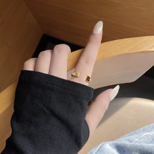 Detail of adjustable gold minimalist ring with 3D heart elements worn by a model