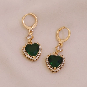 Detail of gold heart earrings featuring green gems surrounded by sparkling small crystals