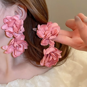 Gros plan de boucles d'oreilles fleur en satin rose aux pétales et textures variés