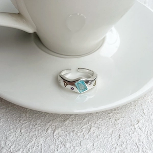 Detail of 925 silver open ring featuring a rectangular blue gem and colorful small stones