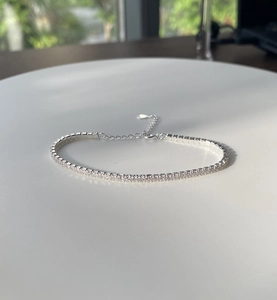 Macro view of silver S925 tennis bracelet with sparkling zircon crystals on a white stand