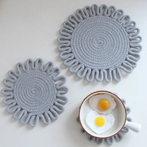 Three grey hand-woven cotton heat-resistant flower table mats in a clean setting