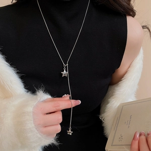 Close-up of a silver Y-shaped star pendant necklace on a black sweater base
