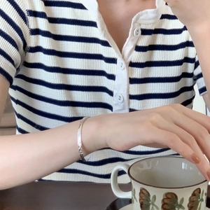 Detailed view of silver minimalist irregular textured bangle on a female wrist