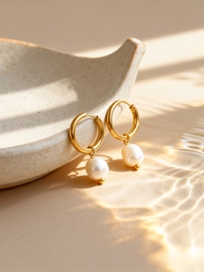 Detail of single freshwater pearl dangle earrings on ceramic tray with water reflections