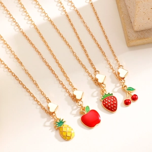 Dettaglio di quattro ciondoli a forma di frutta dorata con ciliegia e fragola smaltate
