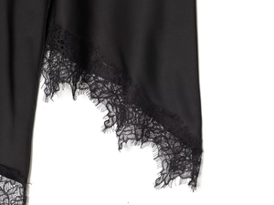 Macro detail of elegant black satin skirt hem with delicate lace stitching and smooth finish