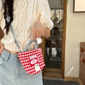 Detail of red and white plaid tote bag featuring a cute cherry logo and blue handles