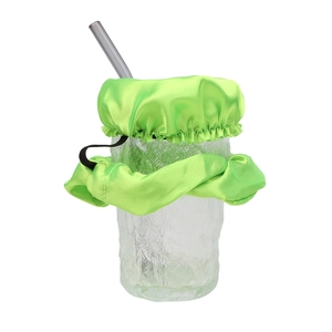Elastic drink cover scrunchie in green silk fabric shown on a glass with straw
